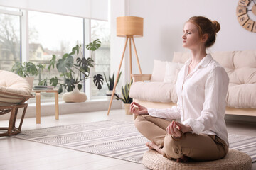 Wall Mural - Woman meditating on wicker mat at home. Space for text