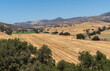 Santa Inez, CA, USA - April 3, 2009: San Lorenzo Seminary. Darker brown mountains and yellow flanks and valley in front where hay was freshly harvested under blue sky.