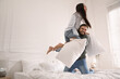 © New Africa - Happy young couple having fun pillow fight in bedroom