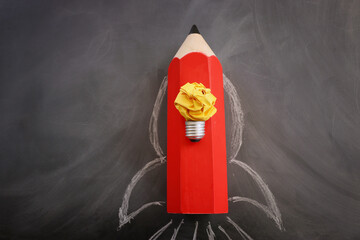 Wall Mural - Education concept image. Creative idea and innovation. Crumpled paper as light bulb metaphor and rocket from pencil over blackboard