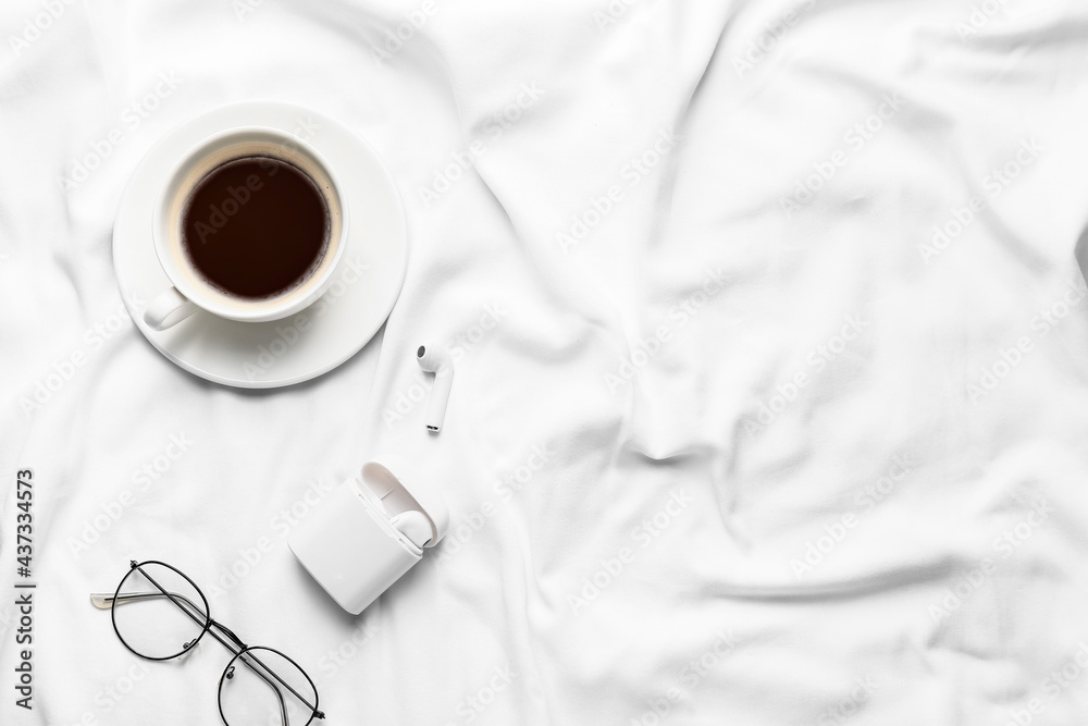 Cup of coffee with earphones and glasses on bed - obrazy, fototapety, plakaty 