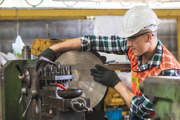 worker is working on a lathe machine in a factory. Turner worker manages the metalworking process of mechanical cutting on a lathe