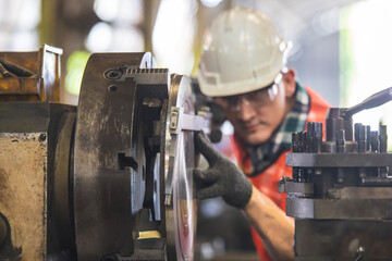 worker is working on a lathe machine in a factory. Turner worker manages the metalworking process of mechanical cutting on a lathe