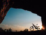 Fototapeta Most - silhouette of a e-bike or bike at sunset in a cave