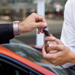 A businessman in black suit  handling car key to the valet service staff. Close up