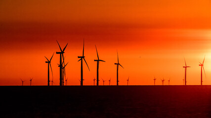 Offshore Wind Turbines set against a sunrise red sky	
