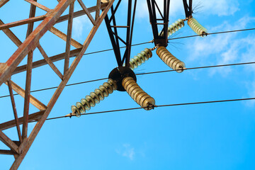 High-voltage line for the transmission of electrical energy. The glass insulators are photographed against a cloudless blue sky.