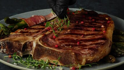 Wall Mural - T bone beef steak, grilled. Presentation of the dish.  The cook is decorating the steak. Close-up on decoration.