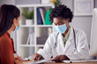 © Monkey Business - Female Doctor In White Coat Wearing Face Mask Having Meeting With Mature Woman Patient In Office