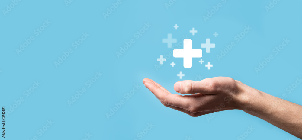 Male hand holding plus icon on blue background. Plus sign virtual means to offer positive thing like benefits, personal development, social network Profit,health insurance, growth concepts - obrazy, fototapety, plakaty 