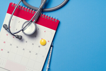 Wall Mural - Top view of stethoscope and calendar on the blue background, schedule to check up healthy concept