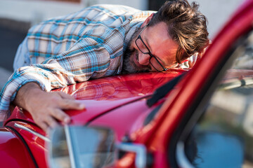 Handsome bearded man is hugging his new car and smiling - love for auto vehicle with adult mature people in love and happy - concept of male and auto