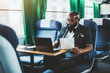 © skyNext - A dapper mature bald bearded black man entrepreneur is using his laptop and holding a document in his hand while sitting on a soft seat of a high-speed intercountry train during his business travel