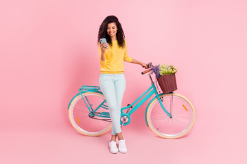 Wall Mural - Full length body size view of pretty cheerful girl with bike using device blogging chatting isolated over pastel pink color background