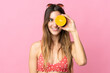 © luismolinero - Young blonde woman over isolated pink background in swimsuit and holding an orange