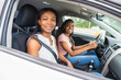 © Louis-Photo - Young black teenage driver seated in her new car with her mother