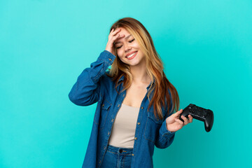 Wall Mural - Teenager blonde girl playing with a video game controller over isolated wall smiling a lot