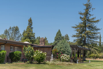 Santa Inez, CA, USA - May 26, 2021: San Lorenzo Seminary. Low built office building set in lawn and garden under blue sky. White Saint Joseph with child statue.