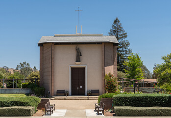 Santa Inez, CA, USA - May 26, 2021: San Lorenzo Seminary. Front facade with statue of the church under blue sky. Set in its green garden.