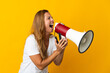 © luismolinero - Middle age brazilian woman isolated on yellow background shouting through a megaphone to announce something in lateral position