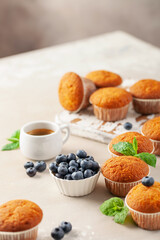 Wall Mural - Muffins or capcakes with blueberries and mint, a cup of coffee on a wooden background.