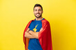 © luismolinero - Young handsome caucasian man isolated on yellow background in superhero costume with arms crossed