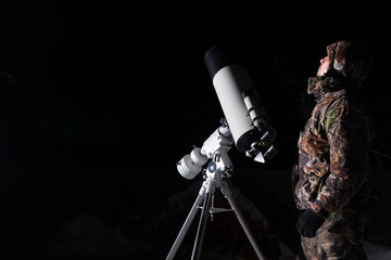 Wall Mural - a man stands next to a telescope against a dark background.
