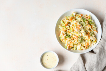 Wall Mural - Coleslaw. Salad made of shredded white cabbage, grated carrot and rhubarb with orange mayonnaise dressing in white bowl, light concrete background.