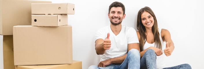 The happy couple moving to the new house and gesture near the white wall