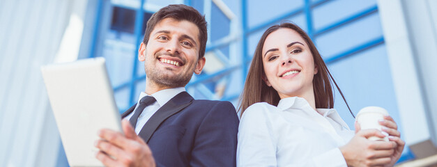 Wall Mural - The man and woman stand with a tablet on the background of the building