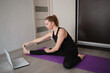 © Aleksandra Iarosh - young woman doing asana at home on yoga mat in front of laptop