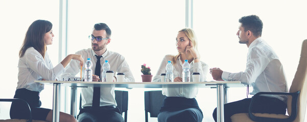 Wall Mural - The four business people sit at the office table near the panoramic window