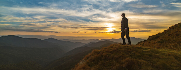 Wall Mural - the man standing on the rock with a picturesque sunset