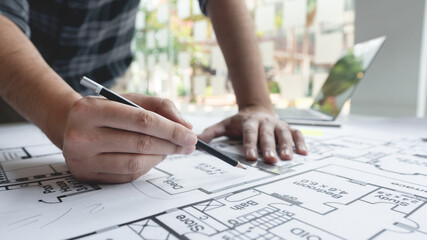 A male architect measuring and marking the scale ratio of sizes of a complicated blueprint