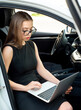 Modern woman businesswoman working on laptop in her car.