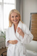 © zinkevych - Blonde woman in a white bath robe looking contented