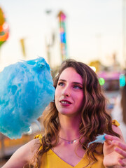 Wall Mural - Portrait of a Caucasian attractive woman with blonde hair eating candy floss on the carousel park