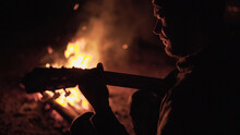Man Is Playing Guitar By The Campfire In Nature. Weekend In Nature By The Fire. Adult Man Is Resting In Forest Near Fire At Night...