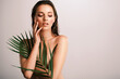 © Valua Vitaly - White woman with healthy skin of body and palm leaves. Tanned body of an attractive girl with green plants. Large palm leaves cover the body.