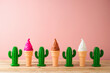 Summer holidays concept with toy ice cream and cactus on wooden table over pink background.