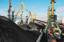 Mountains Of Coal On The Territory Of The Murmansk Commercial Sea Port. The Unloading Of Wagons With Coal And The Loading Of This Coal Into Industrial Sea Ships Are Going All Day And Night.