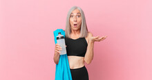 Middle Age White Hair Woman Feeling Extremely Shocked And Surprised With A Towel And Water Bottle. Fitness Concept
