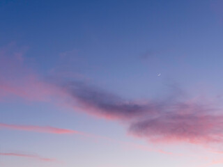 beautiful sunset with pink clouds on clear blue sky with sickle of the waxing moon. colorful panoram