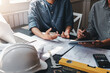 © amnaj - Team engineer and architecture discuss construction together using blueprint tablet at office.