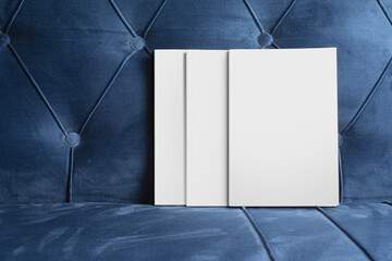 Poster - Books with blank cover on a blue velvet sofa, editable mock-up series ready for design