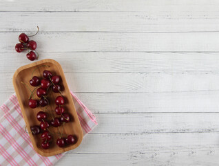 Wall Mural - cherries on wooden plate on white background flat lay