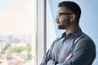 © insta_photos - Headshot portrait of indian confident successful businessman in glasses thinking imagining future corporate financial career standing at office looking at window. Business concept.