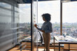 © insta_photos - Young African american executive manager businesswoman writing strategy ideas on sticky notes on whiteboard doing business project presentation in contemporary corporate office with panoramic view.