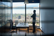Silhouette Of Indian Confident Successful Businessman Thinking Imagining Future Corporate Financial Career Standing At Office Near Window Of High Floor Building With City View On Big Urban Center.