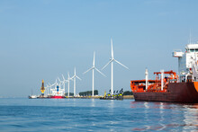 A Seaport On The Outskirts Of Amsterdam With Wind Generators On The Coast And Solar Panels Mounted On Mooring Posts.